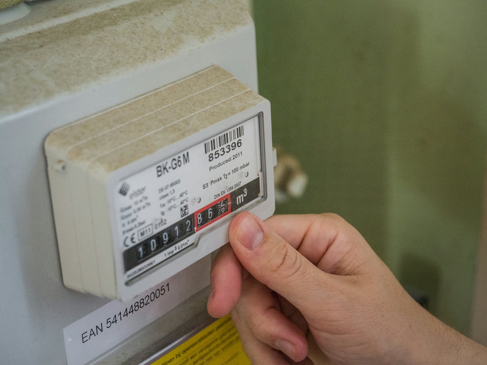 Hand am Gaszähler beim Ablesen des Zählerstands